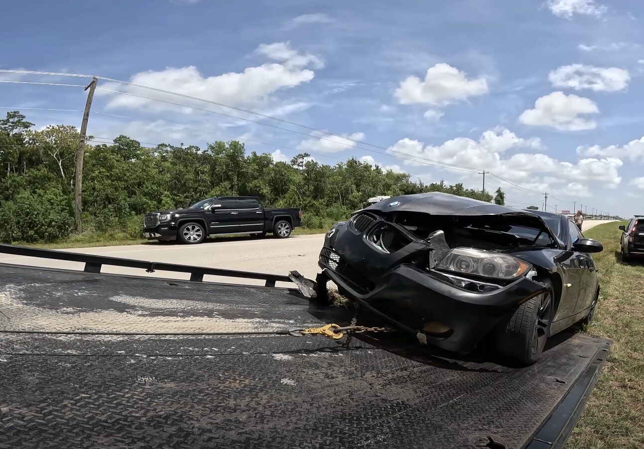 Damaged black sedan being recovered after highway accident