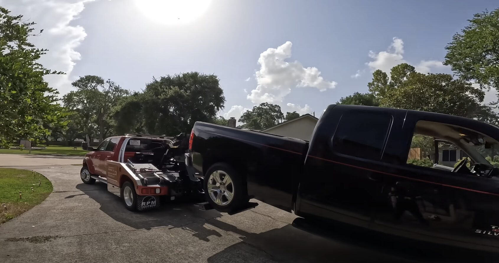 Tow truck providing roadside assistance to pickup truck in residential area