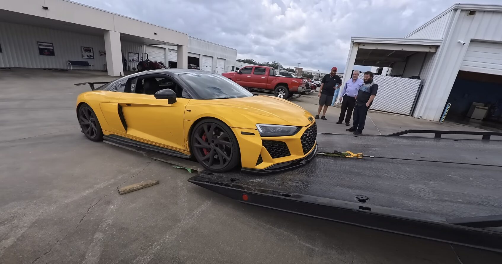 Yellow Audi R8 sports car being loaded onto professional tow truck flatbed